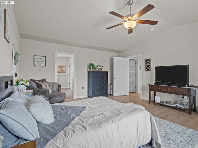 bedroom with baseboards, wood finished floors, ensuite bathroom, and vaulted ceiling