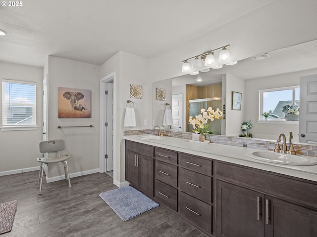 full bath featuring double vanity, wood finished floors, baseboards, and a sink