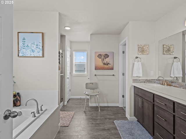 full bathroom featuring wood finished floors, baseboards, walk in shower, a bath, and vanity