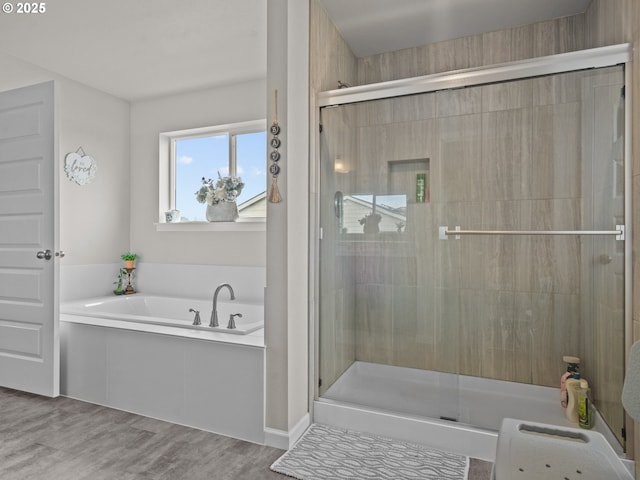 bathroom with a stall shower, a garden tub, and wood finished floors