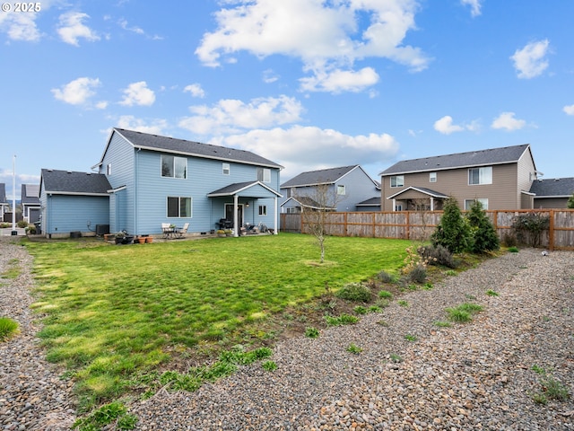 rear view of property featuring a yard, fence, and a residential view