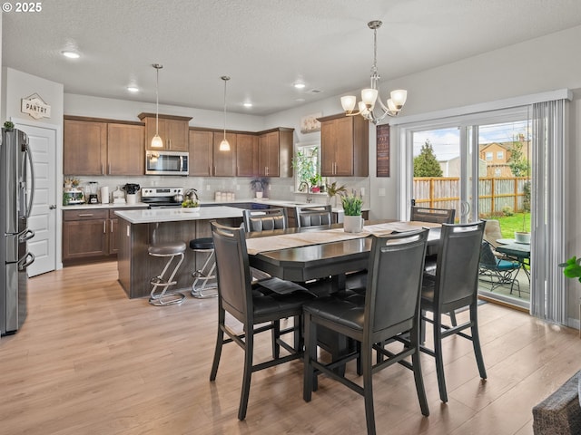 dining area with recessed lighting, a textured ceiling, a chandelier, and light wood finished floors