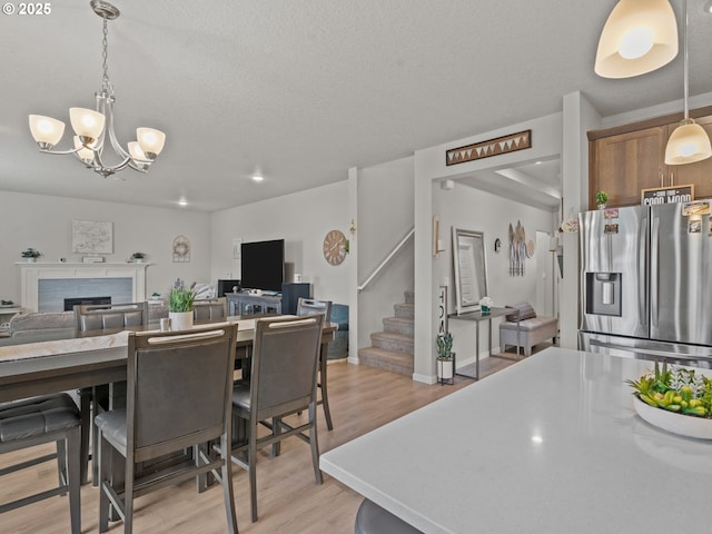 dining room with baseboards, stairs, a fireplace, light wood-style floors, and an inviting chandelier