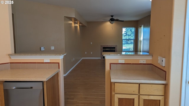 kitchen with light countertops, ceiling fan, a fireplace, and wood finished floors
