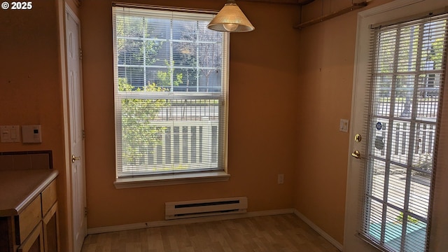 doorway to outside featuring baseboards, plenty of natural light, baseboard heating, and light wood-style flooring