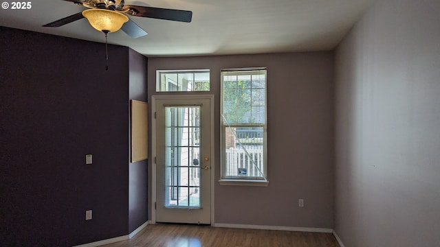 doorway to outside with baseboards, ceiling fan, and light wood finished floors