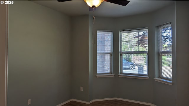 empty room featuring plenty of natural light, baseboards, ceiling fan, and dark wood-style flooring