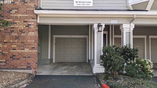 view of exterior entry with brick siding and aphalt driveway