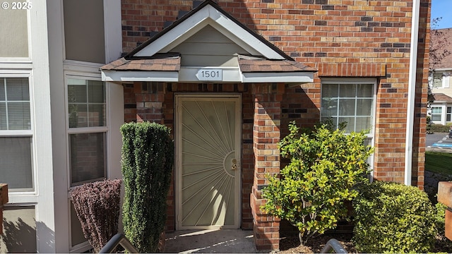 view of exterior entry featuring brick siding