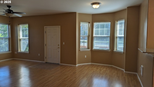 spare room featuring baseboards, light wood-style flooring, and ceiling fan