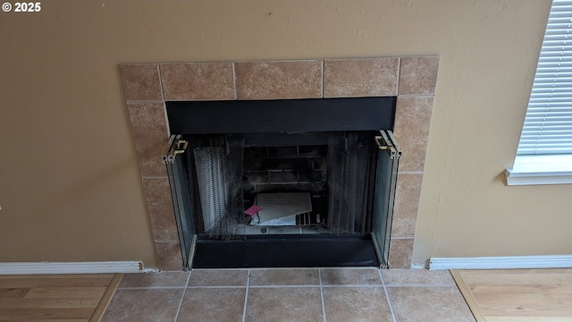 details with a tiled fireplace and baseboards