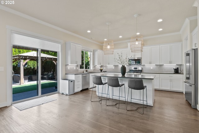 16943 SW Snowdale St, Beaverton, OR 97007 - kitchen with appliances with stainless steel finishes, decorative backsplash, a kitchen island, a sink, and a kitchen breakfast bar