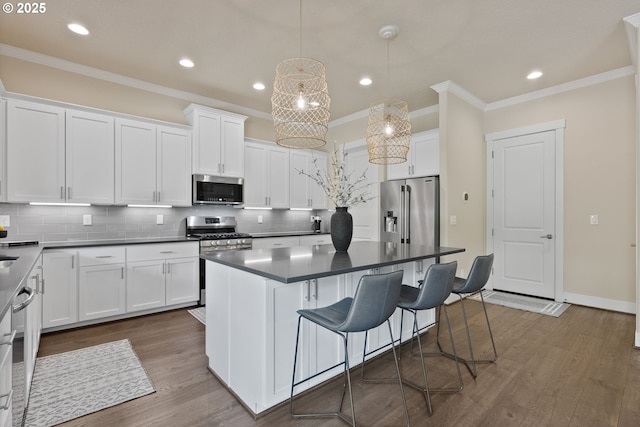 16943 SW Snowdale St, Beaverton, OR 97007 - kitchen with stainless steel appliances, crown molding, dark countertops, recessed lighting, and backsplash