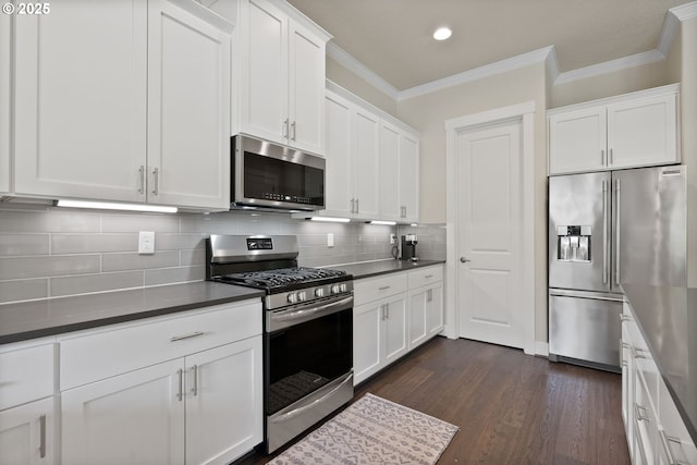 16943 SW Snowdale St, Beaverton, OR 97007 - kitchen with appliances with stainless steel finishes, crown molding, dark wood finished floors, white cabinets, and dark countertops