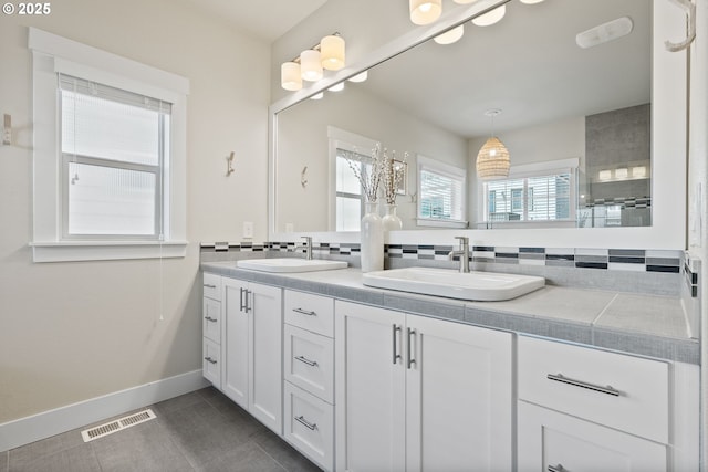 16943 SW Snowdale St, Beaverton, OR 97007 - bathroom with double vanity, backsplash, tile patterned floors, and baseboards