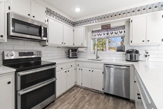 kitchen with decorative backsplash, appliances with stainless steel finishes, wood finished floors, and a sink