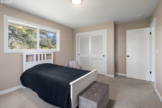 carpeted bedroom featuring a closet and baseboards