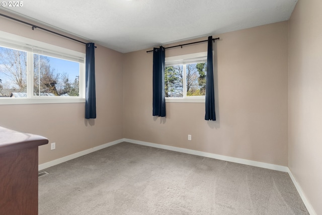 unfurnished room featuring a textured ceiling, baseboards, and carpet