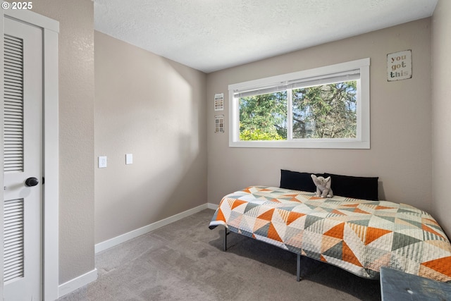 carpeted bedroom with a textured ceiling and baseboards