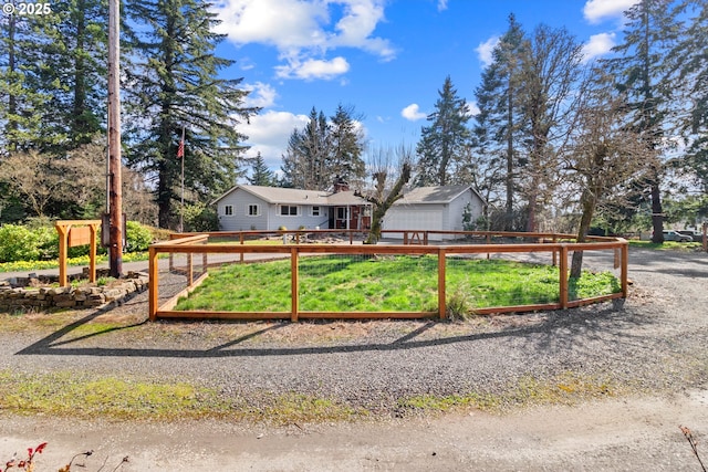 view of front of property featuring a garage, an outdoor structure, a vegetable garden, and fence