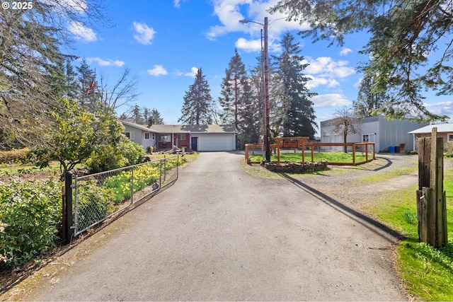 view of front of property with driveway, an attached garage, an outdoor structure, and fence