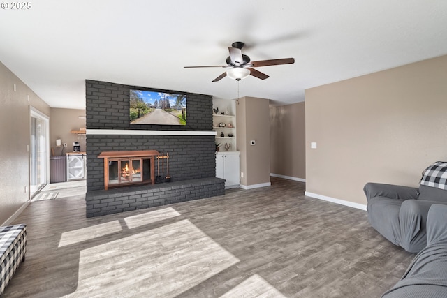 living room with baseboards, wood finished floors, a fireplace, and a ceiling fan