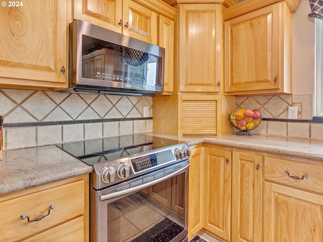 kitchen with decorative backsplash, appliances with stainless steel finishes, and tile patterned flooring