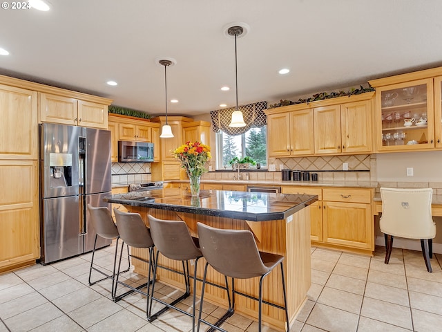 kitchen featuring pendant lighting, a center island, light tile patterned floors, light brown cabinetry, and stainless steel appliances