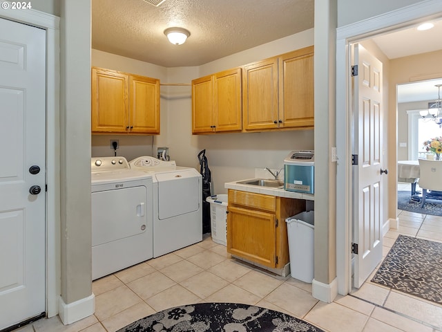 washroom featuring cabinets, washer and clothes dryer, sink, light tile patterned floors, and an inviting chandelier