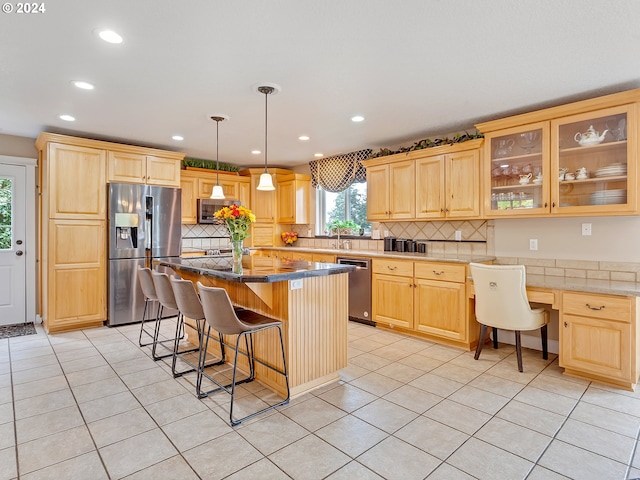 kitchen with appliances with stainless steel finishes, a center island, light tile patterned floors, and a breakfast bar area