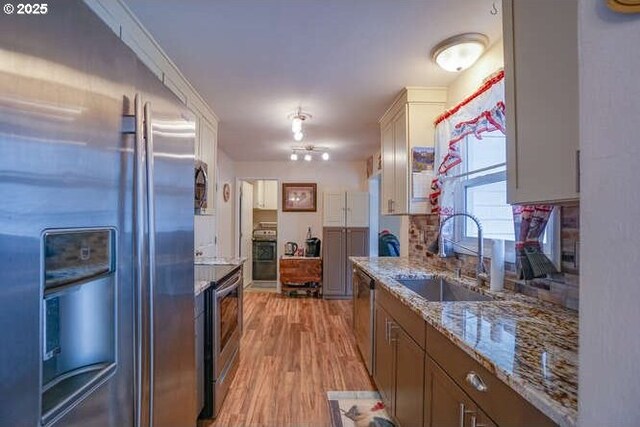 2919 SE 3rd Ave, Camas, WA 98607 - kitchen with appliances with stainless steel finishes, light wood finished floors, light stone counters, white cabinets, and backsplash
