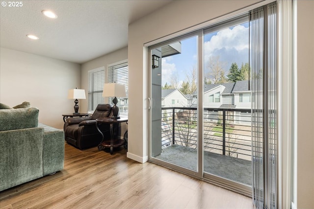 doorway to outside with recessed lighting, a textured ceiling, baseboards, and wood finished floors