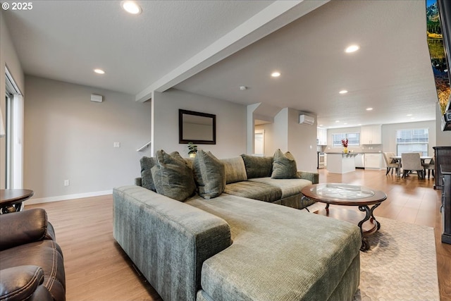 living area with baseboards, a wall mounted air conditioner, light wood-style flooring, and recessed lighting