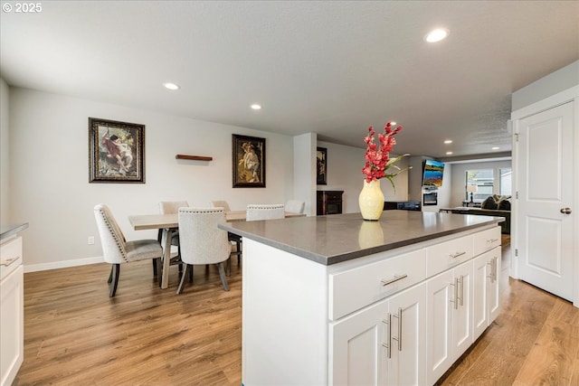 kitchen featuring recessed lighting, a kitchen island, white cabinetry, light wood-type flooring, and dark countertops