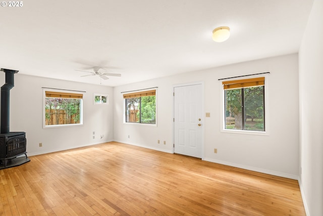 7940 SE 75th Pl, Portland, OR 97206 - unfurnished living room featuring a wood stove, ceiling fan, light wood-style flooring, and baseboards