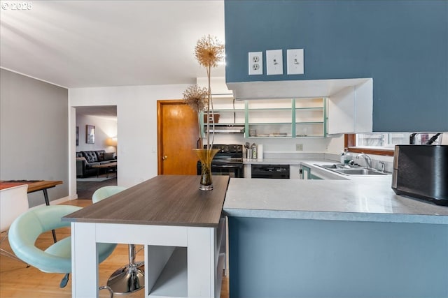 kitchen featuring under cabinet range hood, a peninsula, range with electric stovetop, a sink, and glass insert cabinets