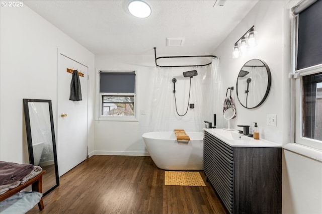 full bath with a textured ceiling, a shower with shower curtain, wood finished floors, vanity, and a freestanding bath