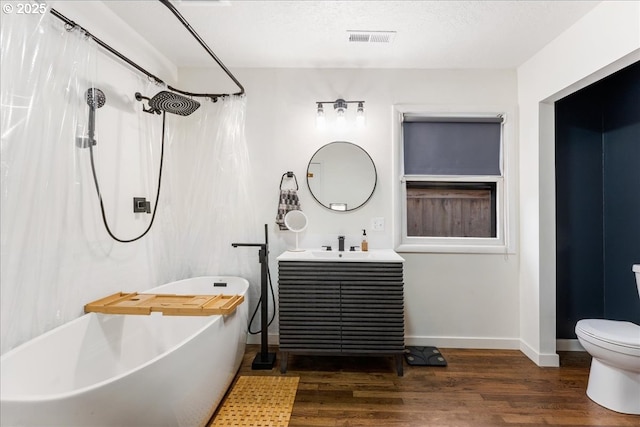 full bath featuring vanity, baseboards, a freestanding bath, and wood finished floors