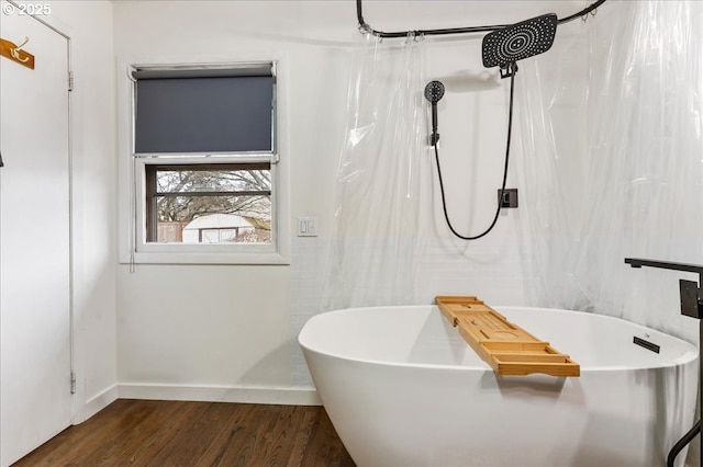 bathroom featuring a freestanding bath, wood finished floors, and baseboards