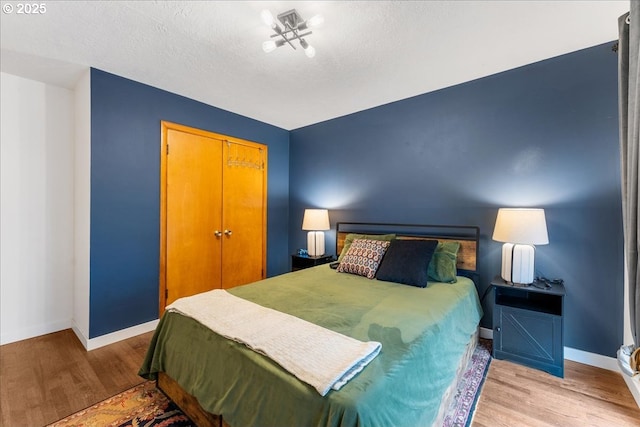 bedroom featuring a closet, baseboards, and light wood finished floors