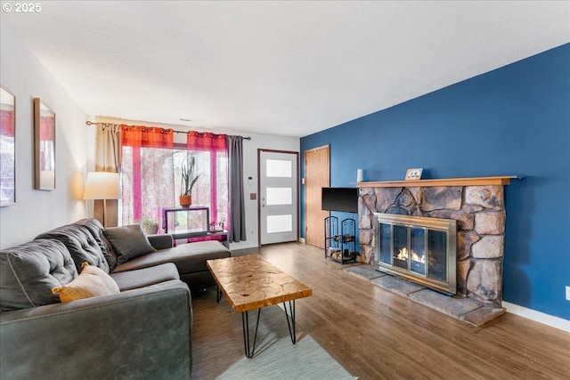 living room featuring a fireplace, baseboards, and wood finished floors