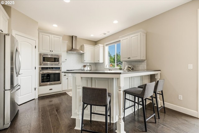 2025 De Vries Way W, Linn, OR 97068 - kitchen with appliances with stainless steel finishes, wall chimney exhaust hood, a kitchen breakfast bar, dark wood-style floors, and recessed lighting