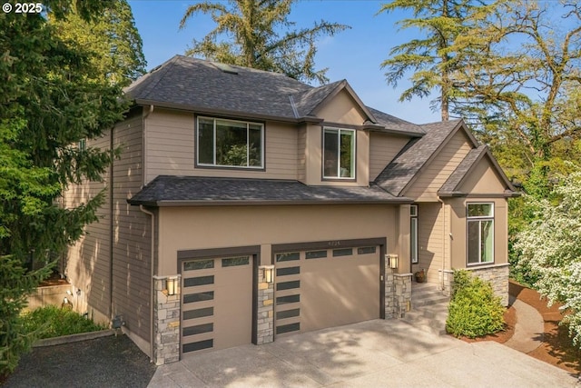 craftsman inspired home featuring roof with shingles, stone siding, a garage, stucco siding, and driveway