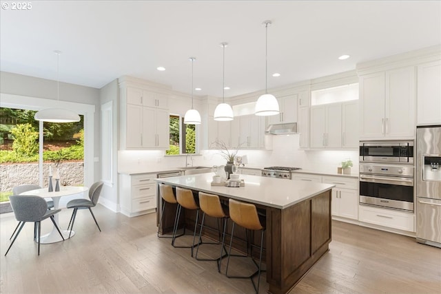 4726 SW 60th Pl, Portland, OR 97221 - kitchen with stainless steel appliances, a sink, under cabinet range hood, backsplash, and a kitchen island