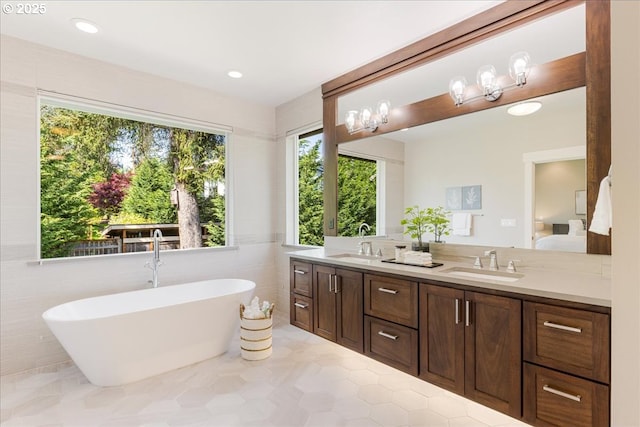 bathroom with a sink, ensuite bath, double vanity, and a freestanding bath