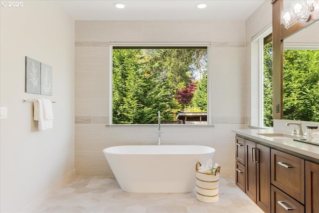 bathroom featuring vanity, recessed lighting, a freestanding bath, and tile walls