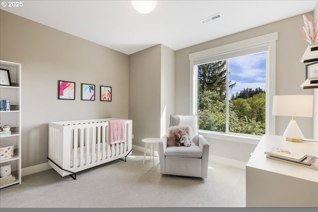 bedroom with carpet floors, baseboards, a crib, and visible vents