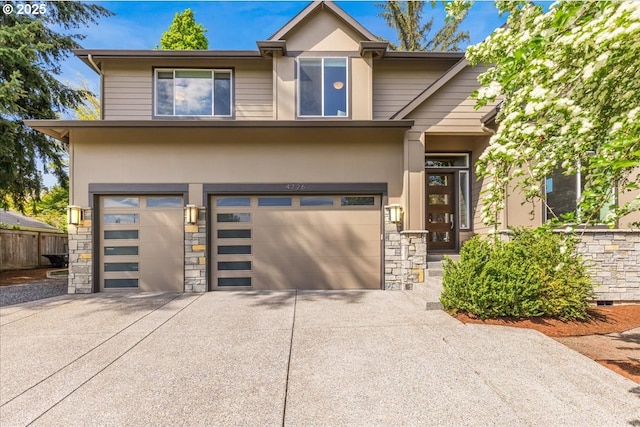 view of front of house featuring fence, concrete driveway, an attached garage, stone siding, and stucco siding