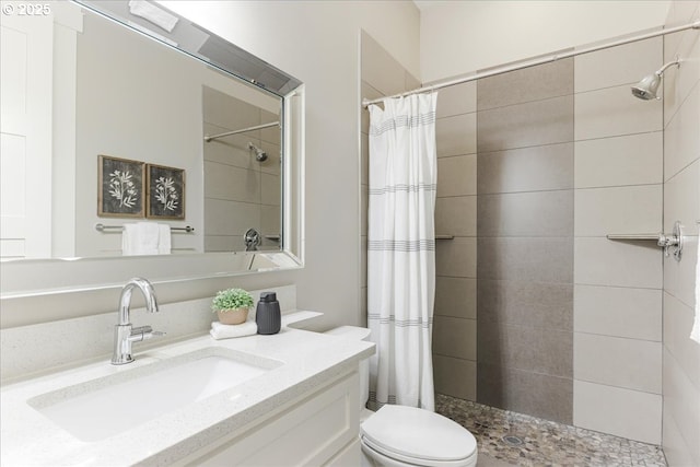 bathroom with vanity, toilet, and tiled shower
