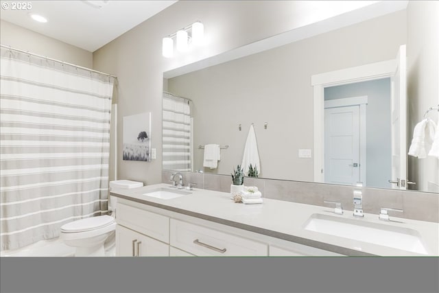bathroom featuring a sink, a shower with curtain, toilet, and double vanity